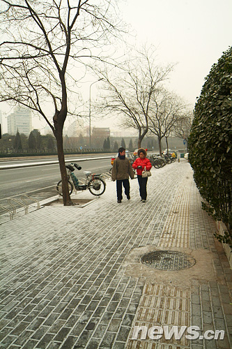 1月17日早上,北京西便门,行人走在小雪覆盖的人行道上.新华网 文涛 摄